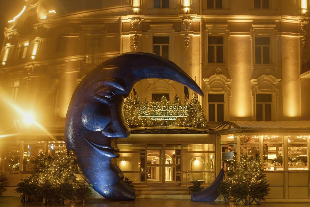 una statua di fronte a un edificio di notte di Radisson Collection Astorija Hotel, Vilnius a Vilnius