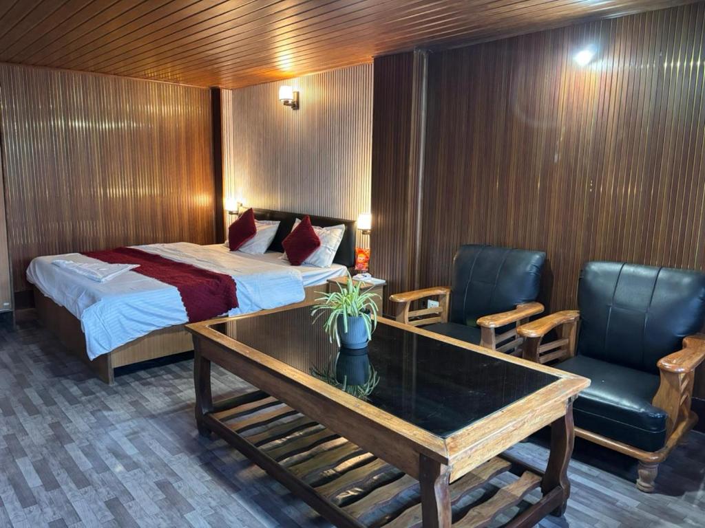 a hotel room with a bed and a table and chairs at P Square Resto Cafe n Stay in Darjeeling