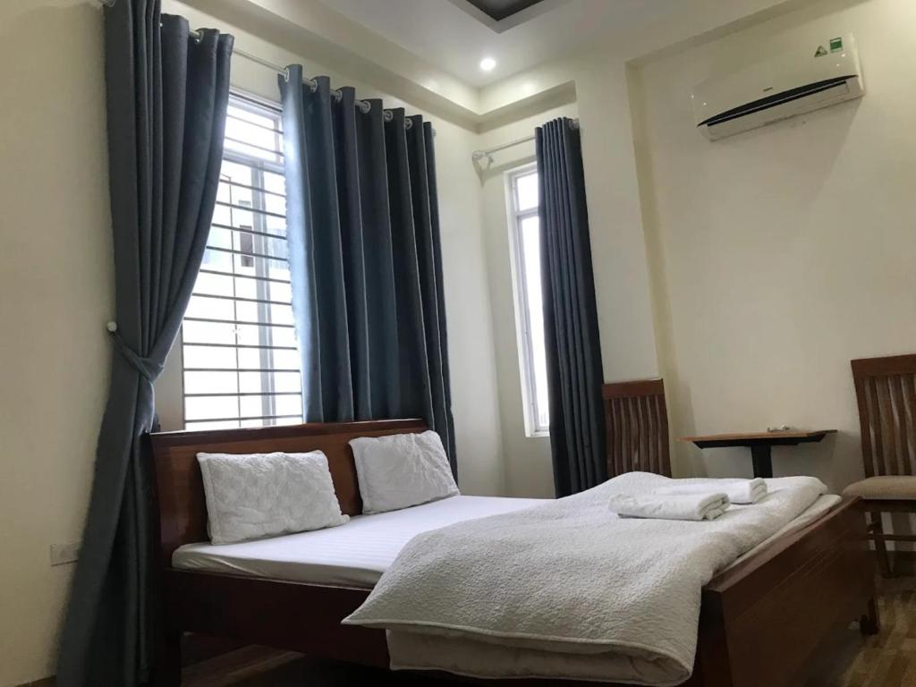 a bedroom with a bed with blue curtains and a window at Bảo Anh Motel in Hải Dương