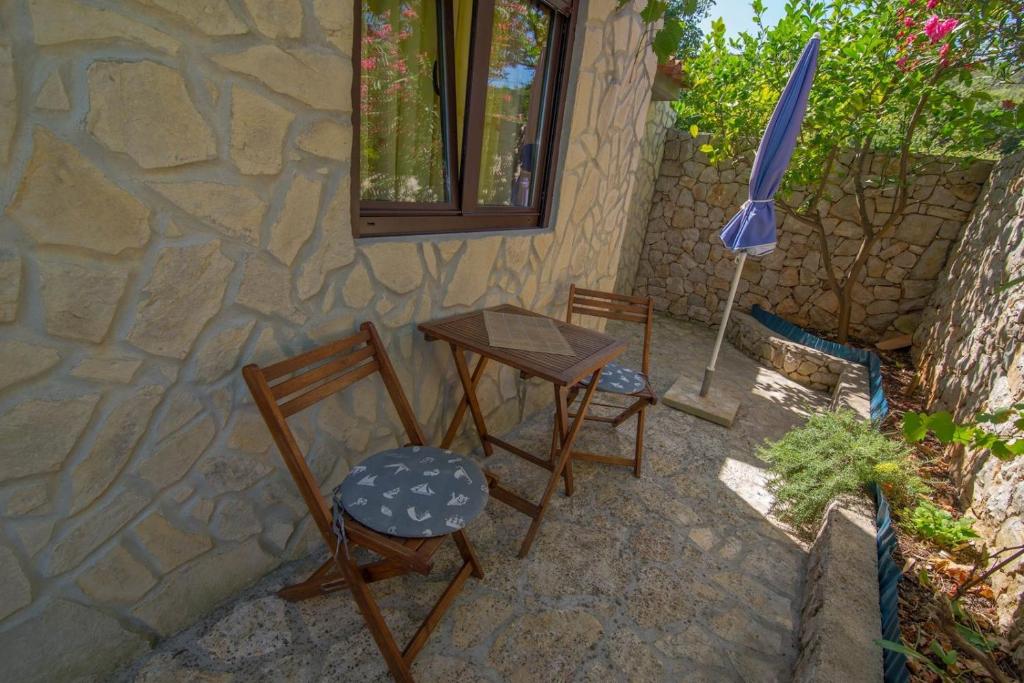 a patio with two chairs and a table and an umbrella at Andrej studio A2 in Veli Lošinj