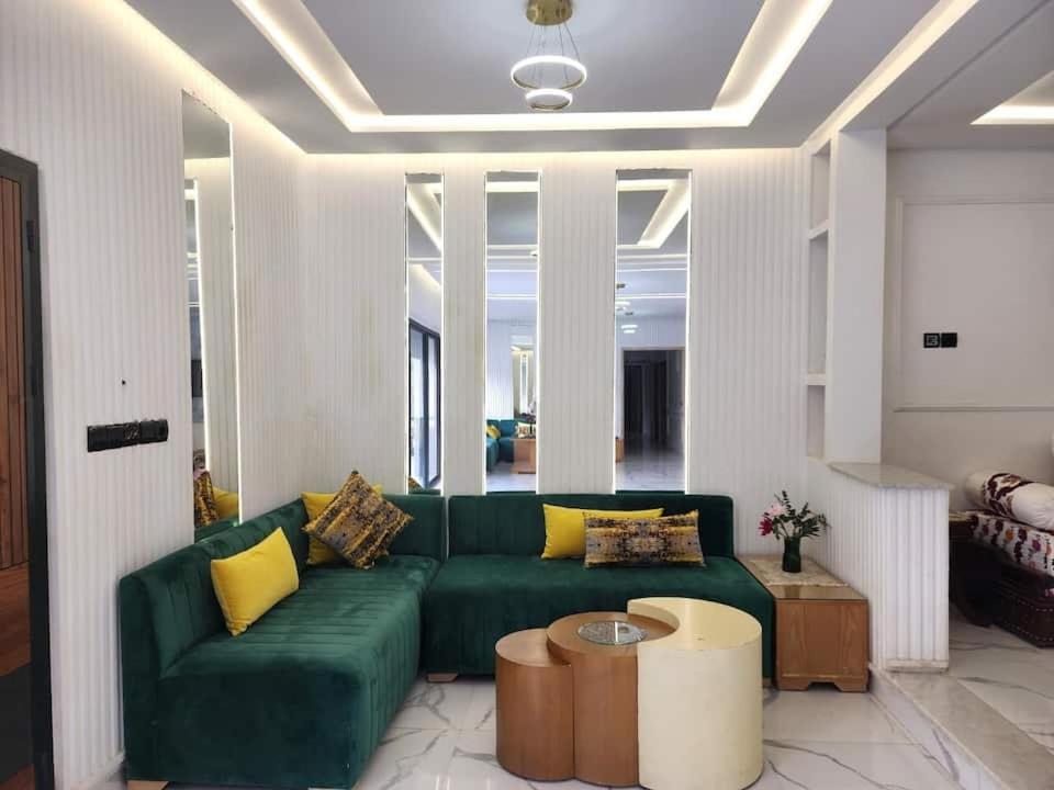 a living room with a green couch and yellow pillows at Villa Luxe Fès avec Piscine & Spa, proche aéroport, Private Hammam in Fès