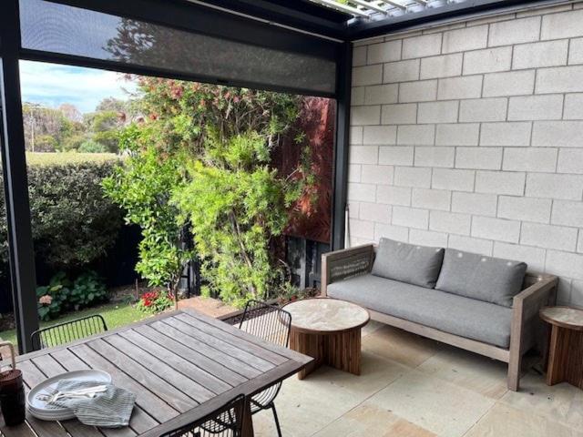 The Ebb Luxury Retreat - Just steps to the beach! في أوشن غروف: فناء مع أريكة وطاولة على الفناء