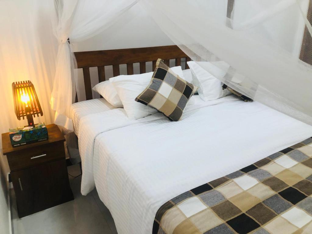 2 Betten in einem Schlafzimmer mit einer Lampe auf einem Nachttisch in der Unterkunft Villa Cinnaro in Ahangama