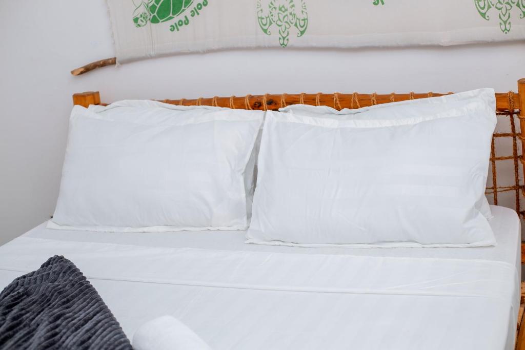 ein Bett mit weißen Kissen und einem hölzernen Kopfteil in der Unterkunft The Hub Train House Apartments in Zanzibar City
