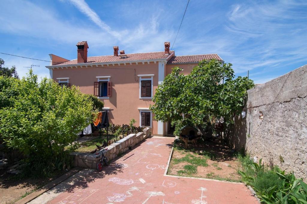 a large house with a stone wall and trees at Andjelka B4-Blue in Mali Lošinj