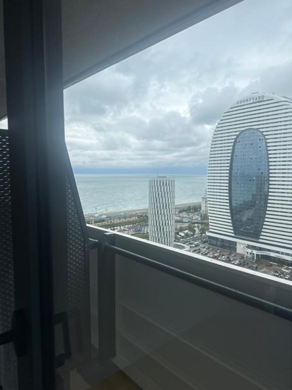 uma vista para o oceano e para os edifícios a partir de uma janela em Orbi city premium plus em Itʼkhvisi