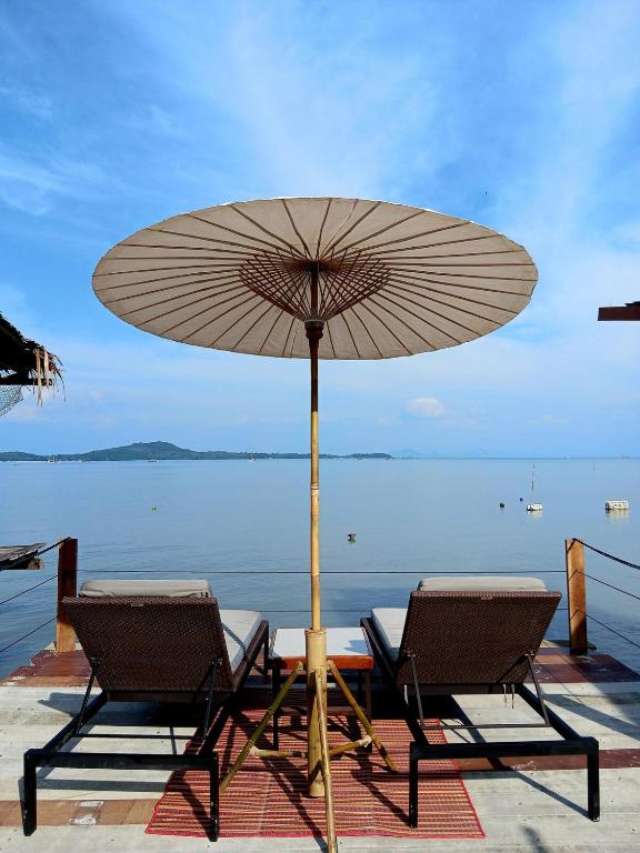 a table and two chairs with an umbrella at Tropical Sea Front House in Ko Po
