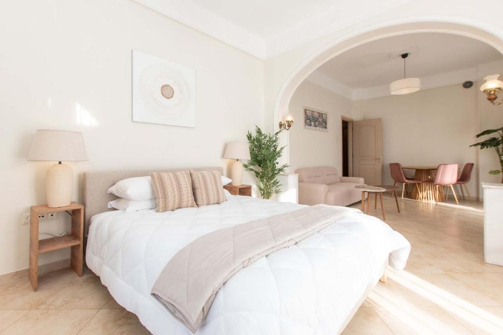 a white bedroom with a large bed and a living room at MainAvenue White Tower in Thessaloniki