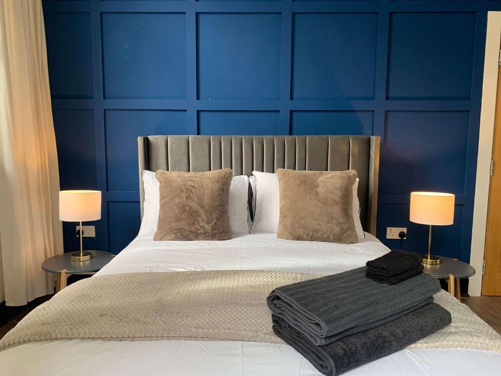 ein Bett mit zwei Lampen und einer blauen Wand in der Unterkunft The Warldorf, King Size and Twin Apartment by The Hive WA1 in Warrington