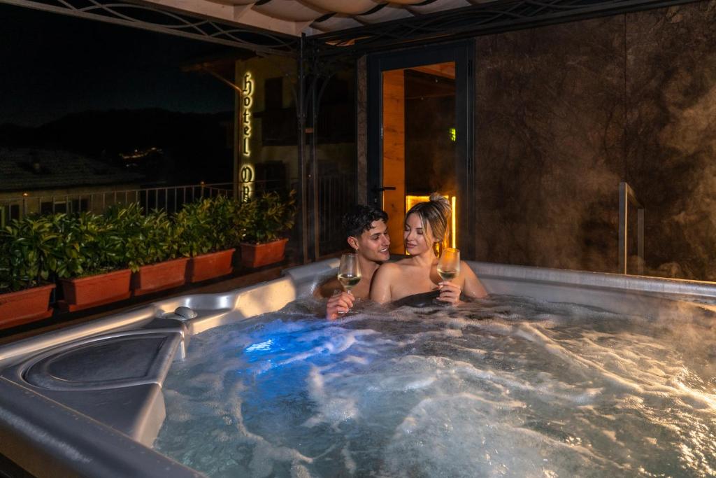 a man and woman sitting in a hot tub with wine at Hotel Opinione Dimora Storica & Private Spa in San Lorenzo in Banale