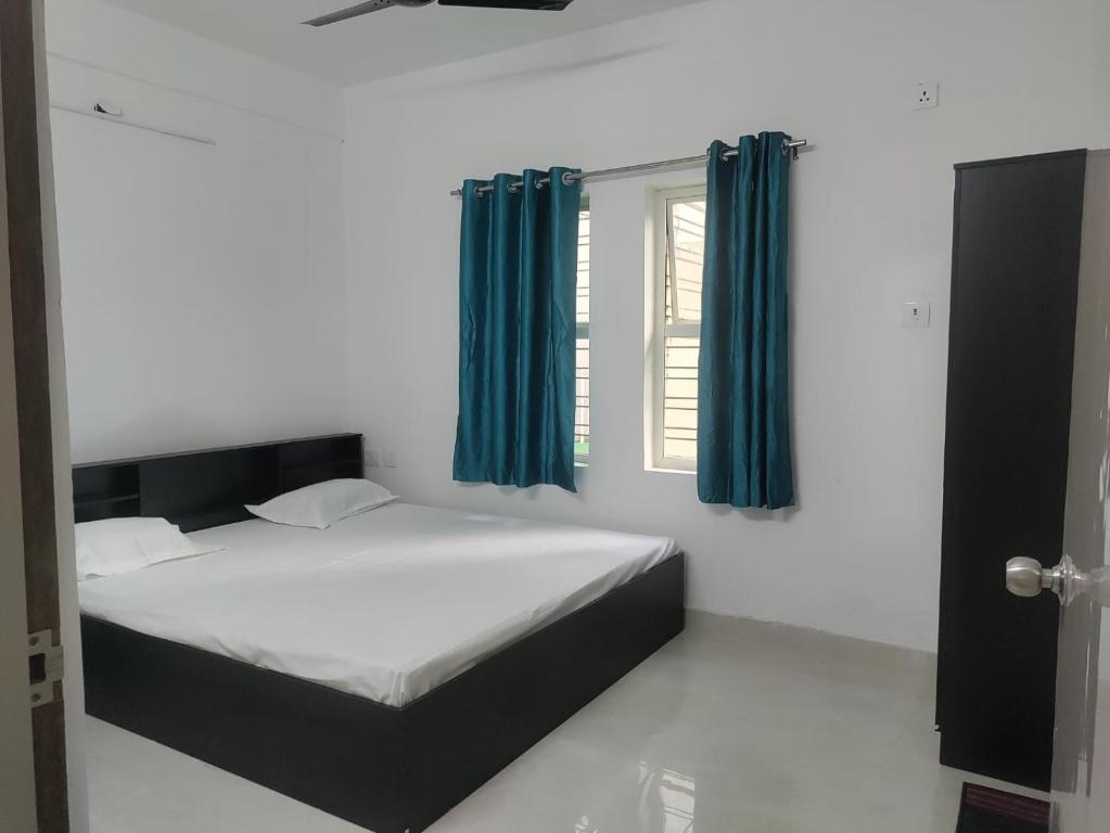 a bedroom with a bed with blue curtains and a window at Stay Place in kolkata