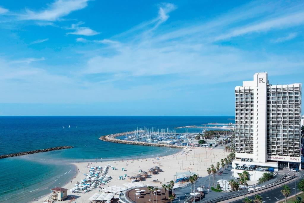 Blick auf einen Strand mit einem Gebäude und dem Meer in der Unterkunft Renaissance Tel Aviv Hotel in Tel Aviv