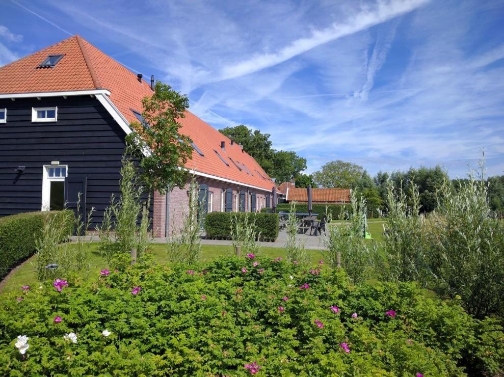 een zwart huis met een rood dak en een tuin bij Group Accommodation for up to 48-persons in Wemeldinge