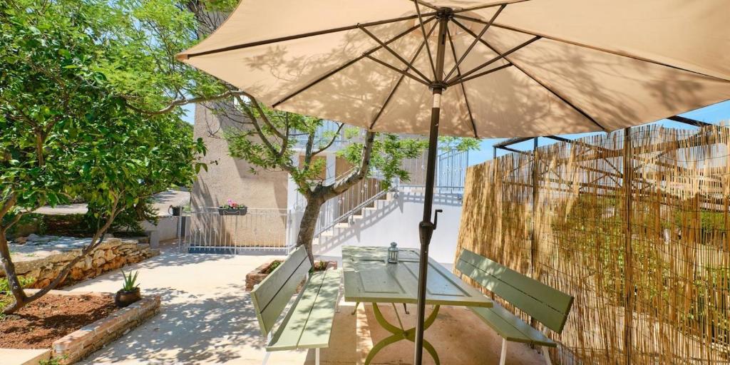 a table with an umbrella next to a bench at Pino 1 in Veli Lošinj
