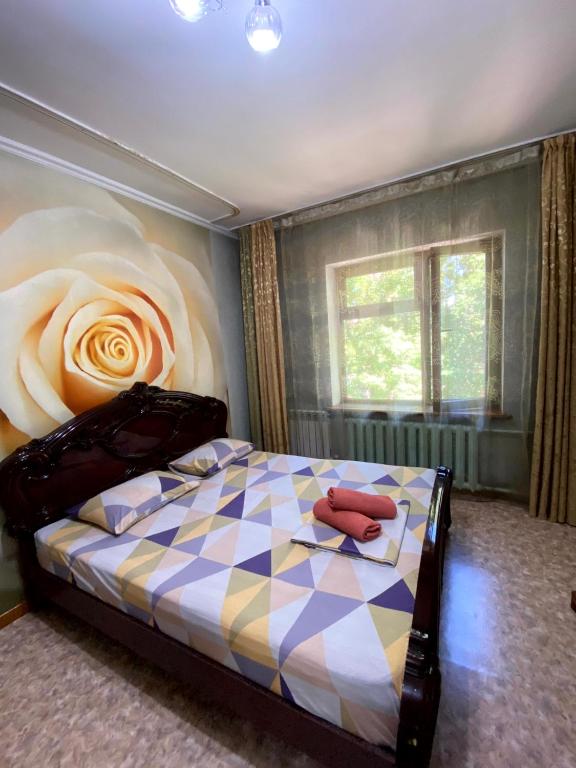 ein Schlafzimmer mit einem Bett, an dessen Wand eine Blume gemalt ist in der Unterkunft Иляева 40 парк Кен Баба in Schymkent