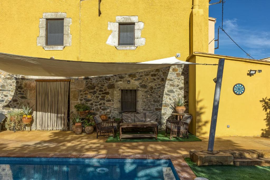 un edificio giallo con un patio con piscina di El Figuerar a San Juan de Palamós