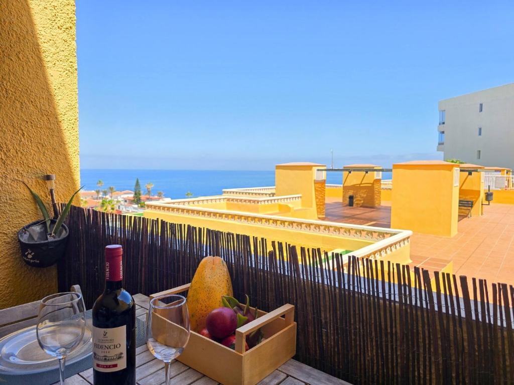 a table with a bottle of wine and a basket of fruit at Arena Beach by HelloApartments in Puerto de Santiago