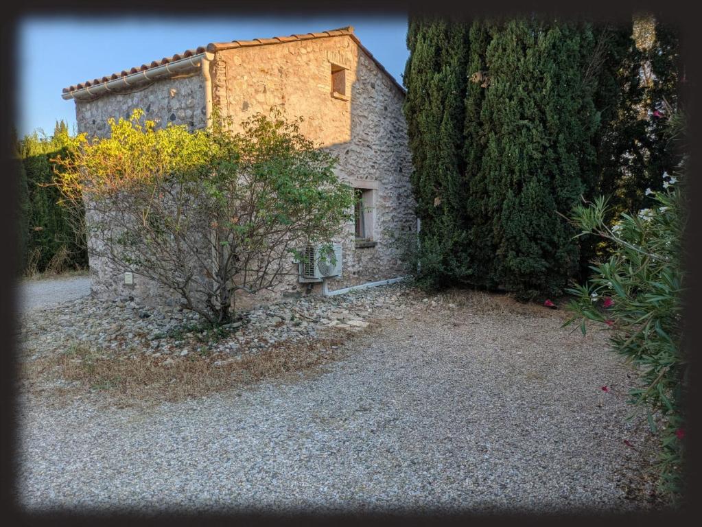 an old stone building next to a large tree at Le Mas des Condamines in Canet