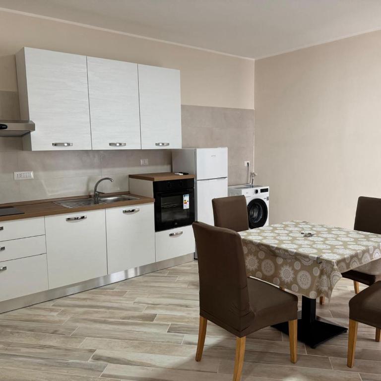 a kitchen with white cabinets and a table and chairs at Casa Vacanze Vienna in Boscotrecase