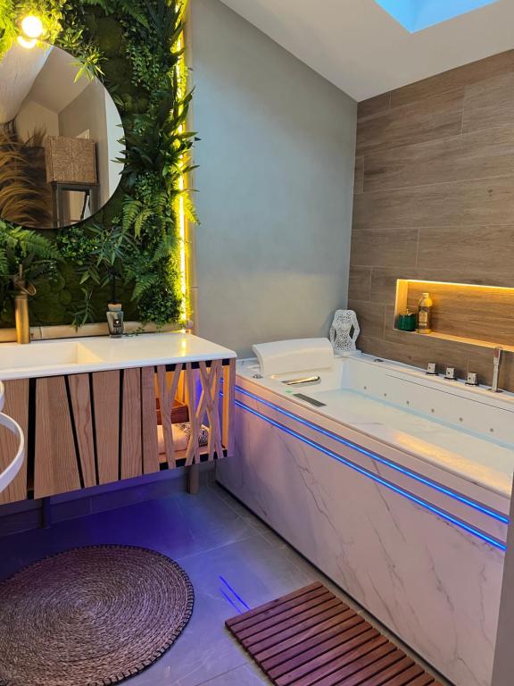 a bathroom with a tub and a large mirror at La Parenthèse Balnéo in Donzère