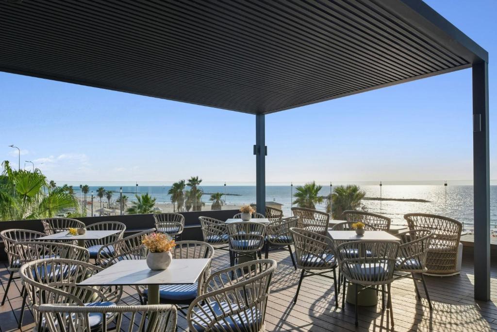 een terras met tafels en stoelen en uitzicht op de oceaan bij Renaissance Tel Aviv Hotel in Tel Aviv