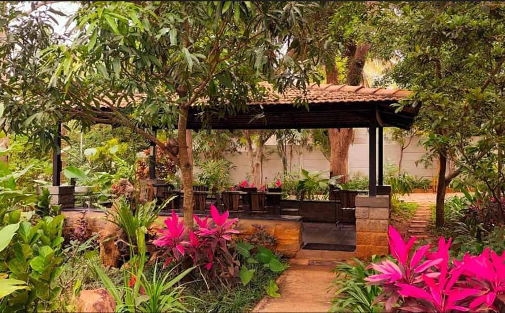 Trisara Boutique Stay في ميسور: جناح في حديقة مع زهور وأشجار وردية اللون