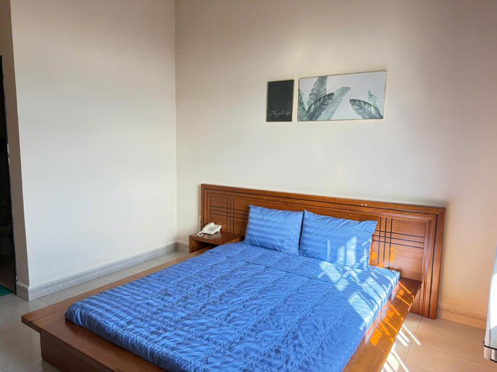 a bedroom with a bed with a blue comforter at Khách Sạn Đối Ngoại Biên Phòng in Buon Ma Thuot