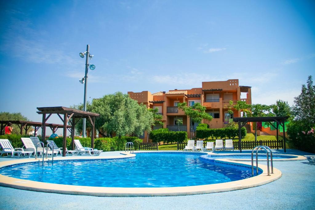 a swimming pool with chairs and a building in the background at Montemar Natura Resort in Peñíscola