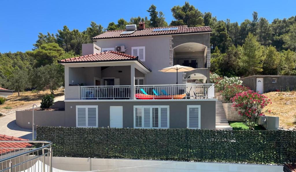 a white house with a balcony and an umbrella at Villa Bell'Aria Korcula in Vela Luka
