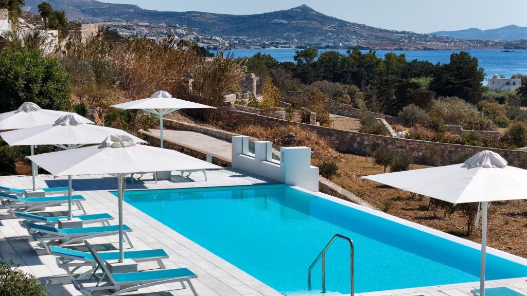 a swimming pool with chairs and umbrellas at Kriolithos Houses in Parikia