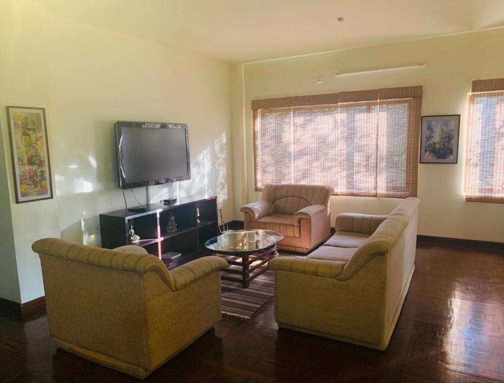 Una sala de estar con dos sofás y un televisor. en Blissful Boudha Apartment, en Katmandú
