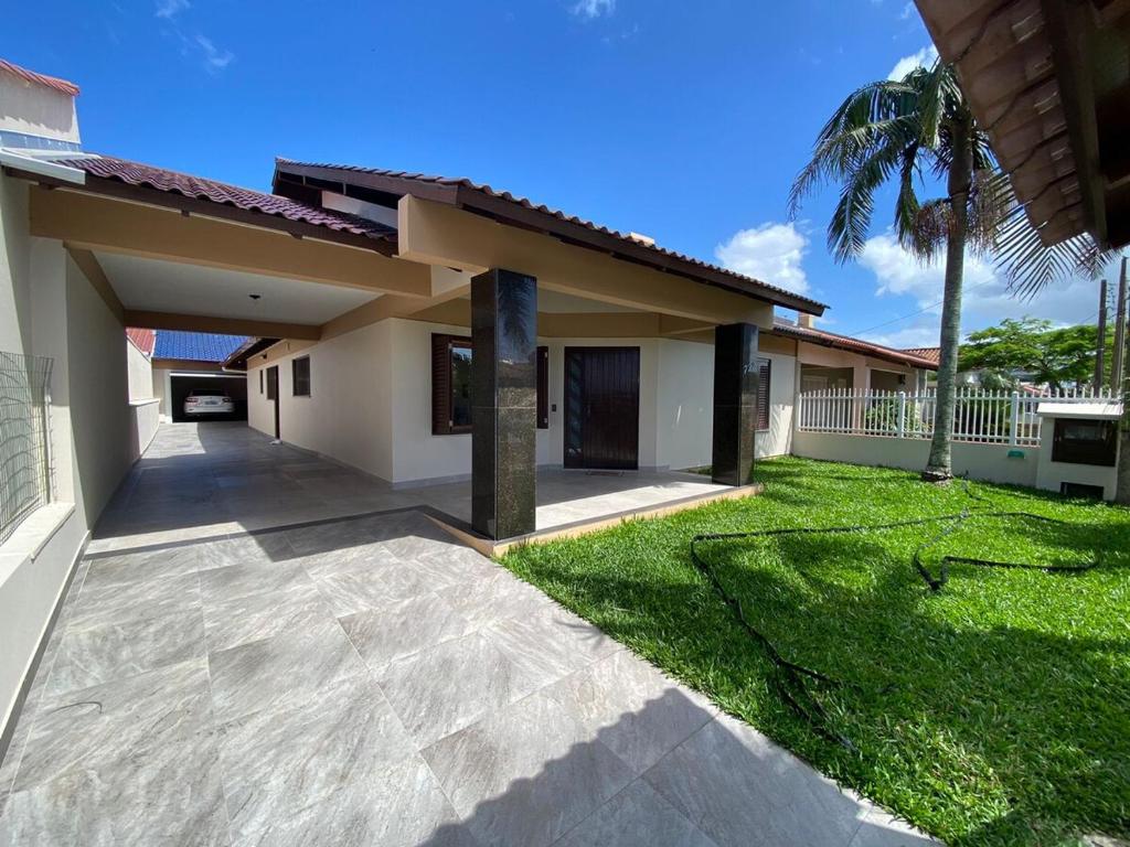 a house with a patio and a grass yard at Fresh house enjoy the beach in the summer! in Capão da Canoa