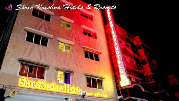 a tall red building with a neon sign on it at Shreekrishna Hotels & Resorts Pvt Ltd in Kolkata