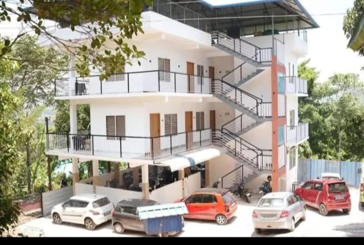 un bâtiment avec des voitures garées devant dans l'établissement Jerusalem Home Saty, à Idukki