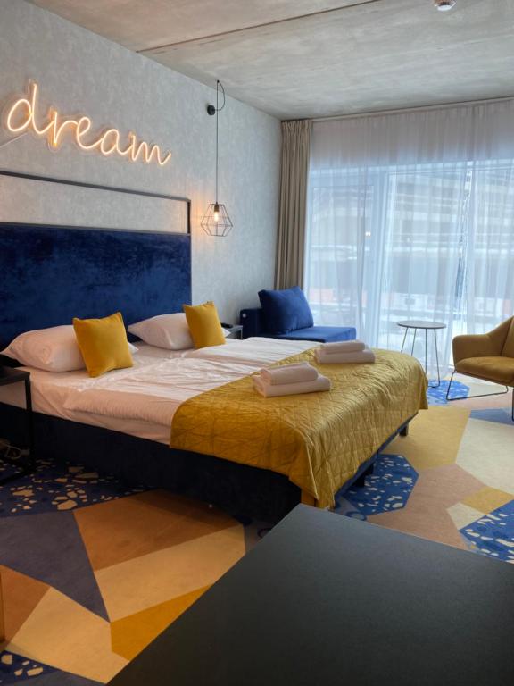 a hotel room with a large bed with yellow pillows at SleepWell Apartments Czarna Góra in Sienna