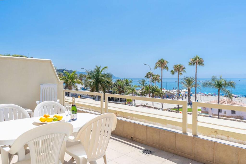 a table and chairs on a balcony with a view of the beach at Luxury, Frontline Burriana Beach, Nerja in Nerja