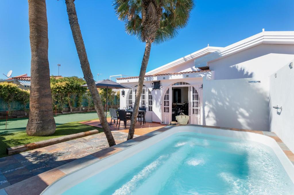 ein Swimmingpool vor einem Haus mit Palmen in der Unterkunft Exclusive Villa with Heated Pool in Maspalomas