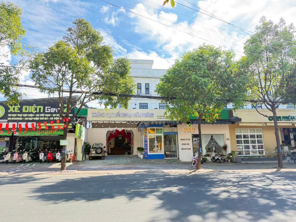 eine Straße mit einem Gebäude mit Geschäften und Bäumen in der Unterkunft Khách Sạn Đối Ngoại Biên Phòng in Buon Ma Thuot