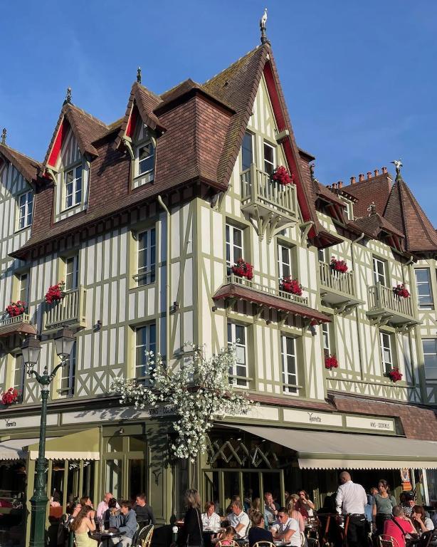 a large building with people sitting outside of it at Villa Henriette in Cabourg
