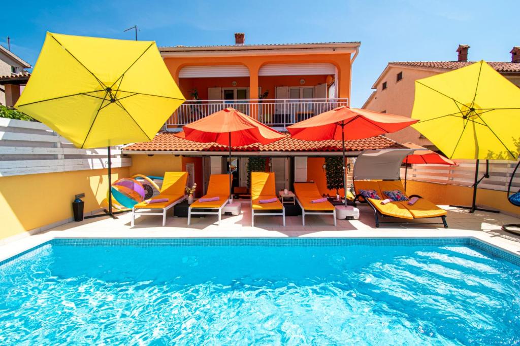a swimming pool with umbrellas and chairs and a house at Vila Andja in Banjole,Istrien by Istrabook in Banjole