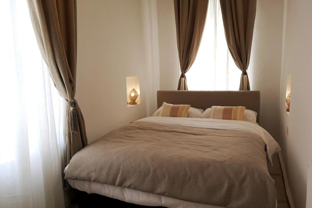 um quarto com uma cama grande com duas janelas em Riad de charme l'Oasis d'Essaouira - Suite Luxe em Essaouira