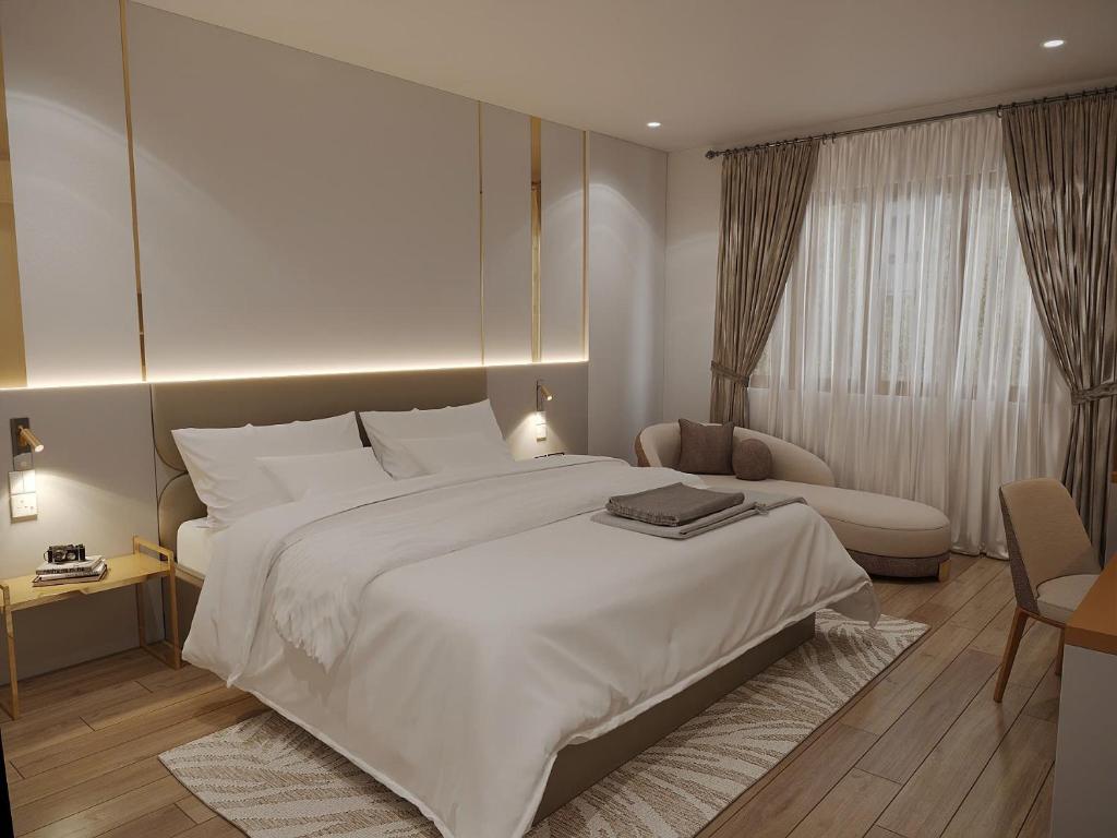 a bedroom with a large white bed and a chair at MAYS Grand Hotel & Spa - Ben Thanh in Ho Chi Minh City