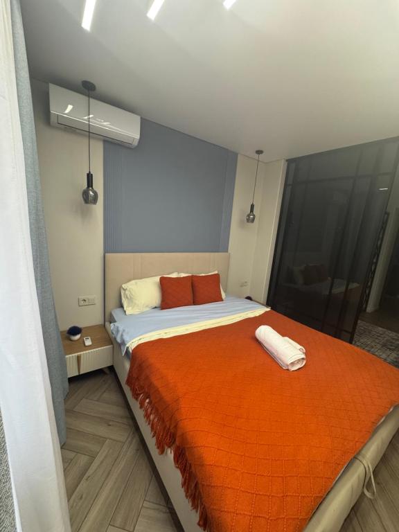 una camera da letto con un letto grande con una coperta arancione di Designer apartment opposite the Airport a Almaty