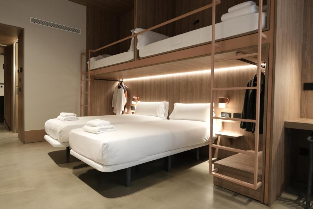 Un dormitorio con dos literas con sábanas blancas. en CASA ROMA Hostel Boutique, en Tarragona