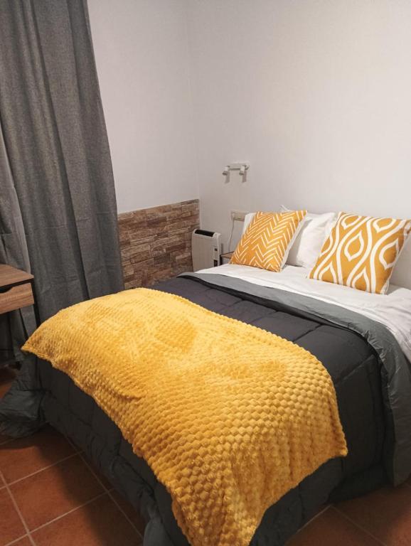 a bedroom with a bed with a yellow blanket on it at Apt Santa Cruz de Caravaca in Caravaca de la Cruz