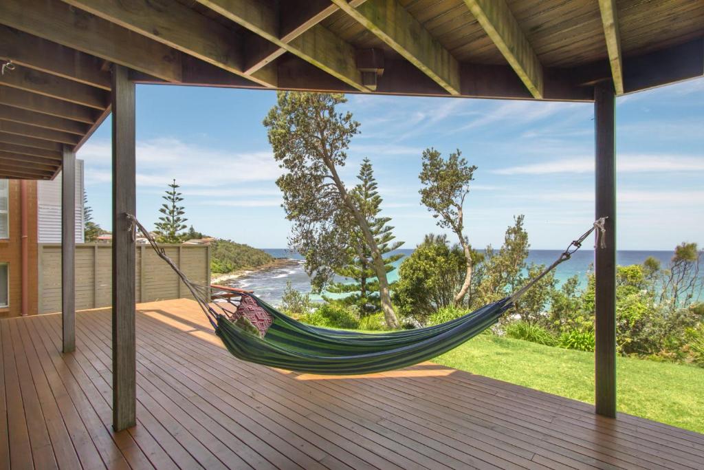 a hammock on a deck with a view of the ocean at Sticks by the Sea - pet-friendly coastal home in Manyana