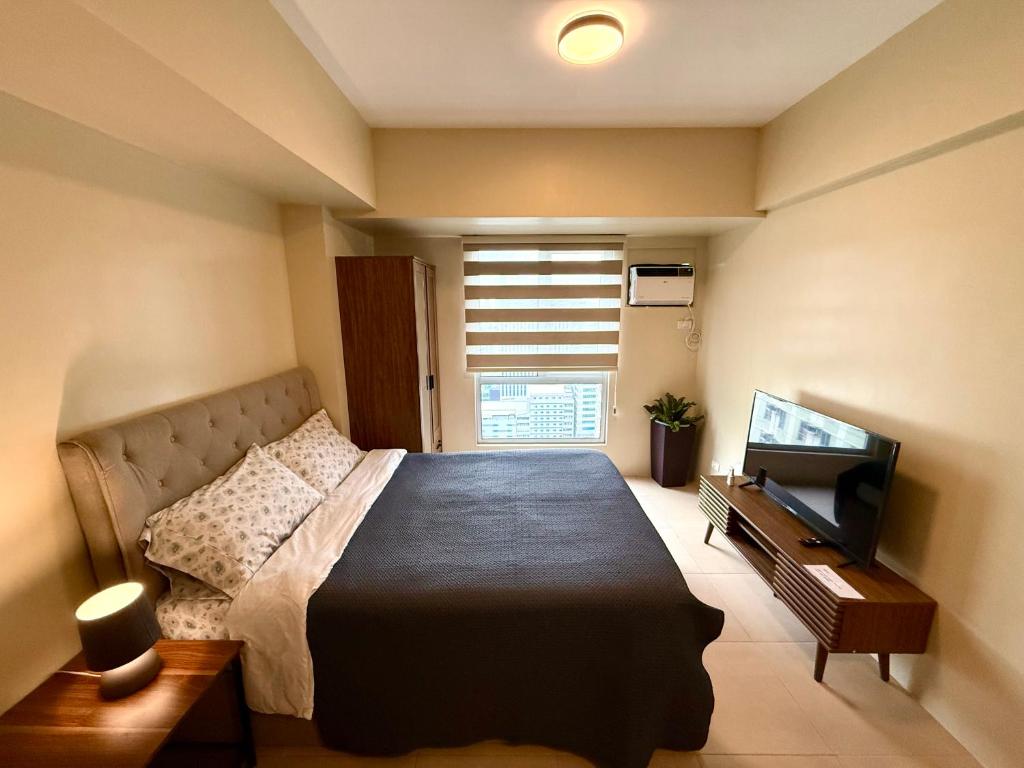 Cebu Minimaluxe Studio Condotel By Go2 Stays في مدينة سيبو: غرفة نوم بها سرير كبير وتلفزيون