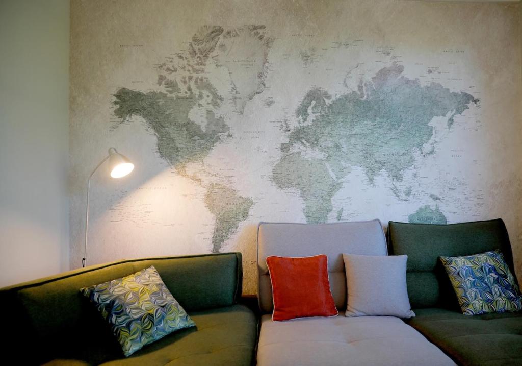 a couch with pillows and a world map on the wall at LE CEDRE Maison bord de LOIRE 4 in Muides-sur-Loire