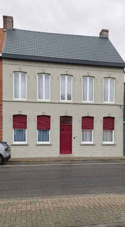 a white building with red doors on a street at Wervik-94 in Wervik