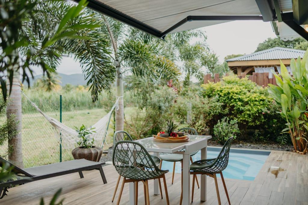 a patio with a table and chairs and a pool at Les Villas Mandju in Sainte-Rose